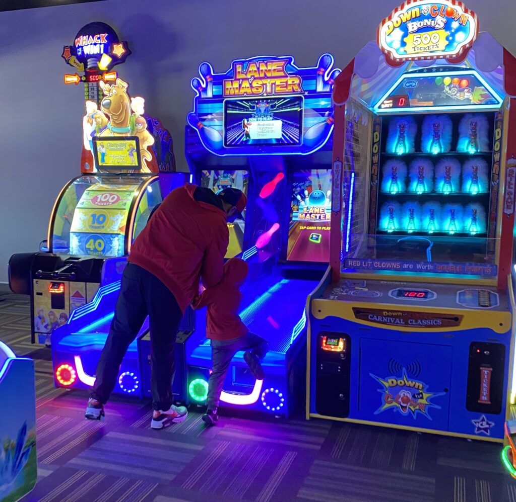 Child playing arcade basketball game indoors.