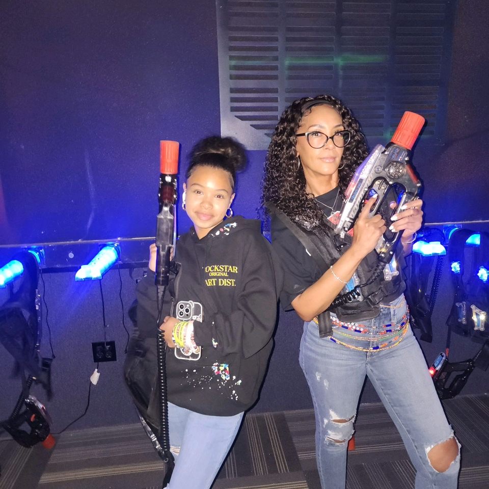 Two people holding laser tag guns in a neon-lit arena.